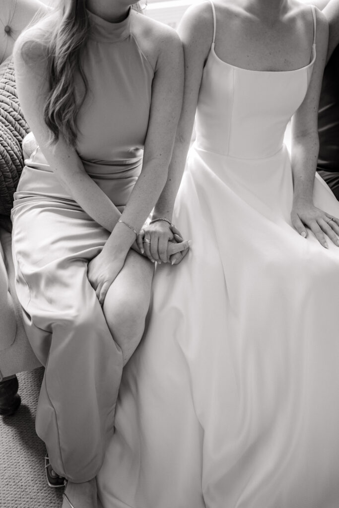 close up of sister and bride holding hands