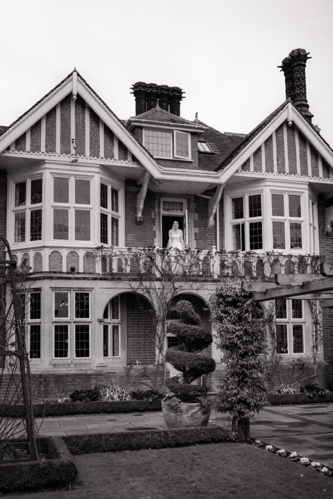 bride standing on balcony outside baddow park house